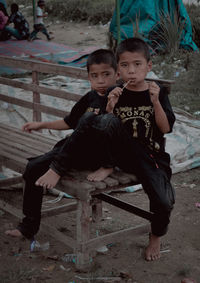 Full length of boy sitting on footpath