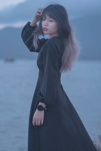 Young woman standing against sea