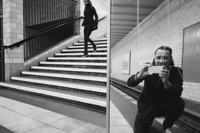 Reflection of man photographing by mirror at subway station