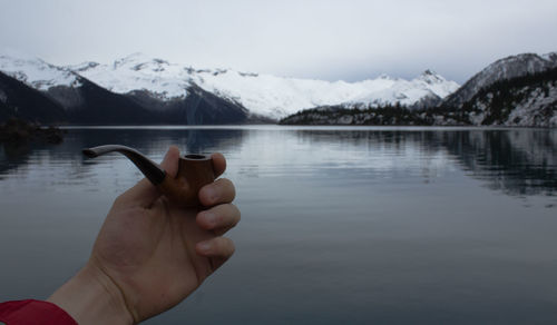 Close-up of hand holding ice over lake