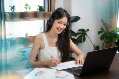 Young woman using phone while sitting on table at home