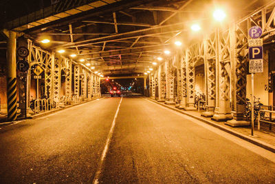 Empty road along illuminated street lights at night