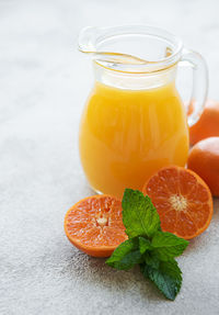 Jug of fresh orange tangerine juice with fresh fruits