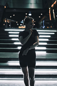 Woman standing on illuminated staircase at night