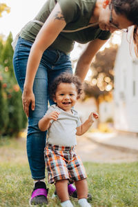 Smiling boy with mother standing at lawn