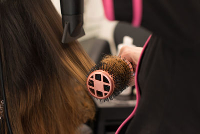 Midsection of hairdresser drying woman hair