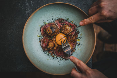 Cropped hand eating of food served on table