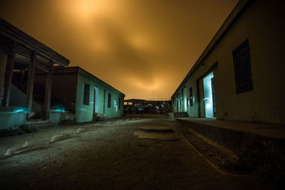 Footpath amidst houses against sky at night