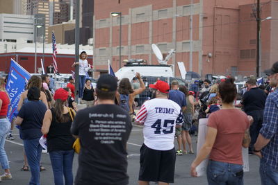 Rear view of people standing on street in city