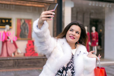 Portrait of smiling young woman using smart phone outdoors