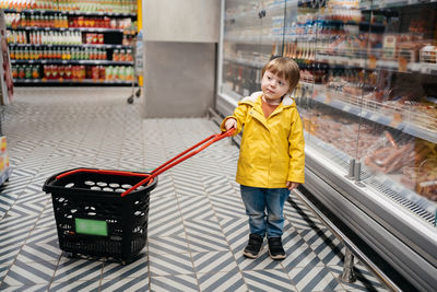 Full length of boy with luggage standing in store