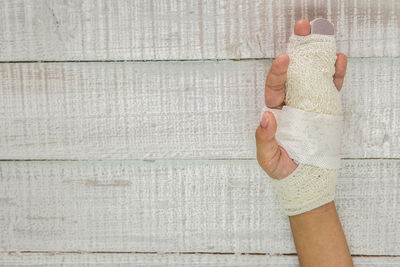 Close-up of hand holding paper against wall