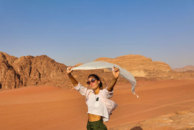 Young woman with white scarf in the wind on wadi rum desert at sunset, jordan, copy space