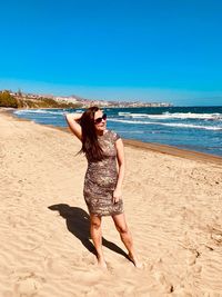 Portrait of smiling woman standing at sandy beach during sunny day