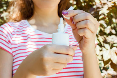 Midsection of woman holding nasal spray while standing in park