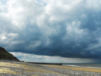 Scenic view of beach against cloudy sky