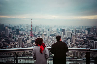 Rear view of people looking at city buildings against sky