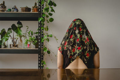 Rear view of woman sitting against wall