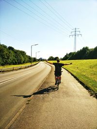 Man riding bicycle on road against clear sky