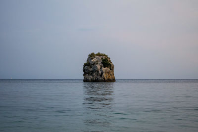 Rock formation in sea against sky