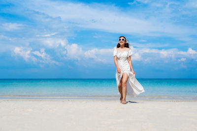 Woman standing at beach against sky