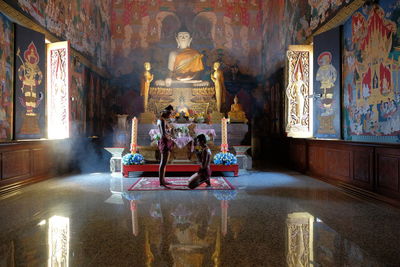 Side view of shirtless men praying in buddhist temple