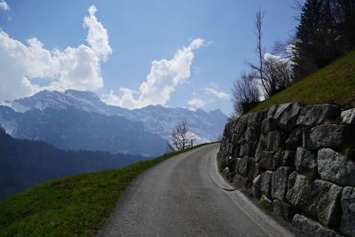 Empty road along landscape against sky