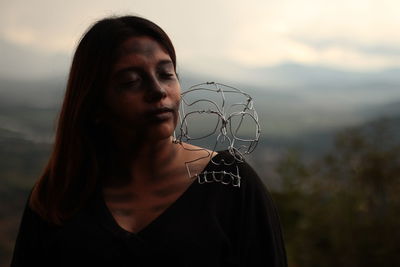 Woman with metal skull on shoulder while standing outdoors during sunset