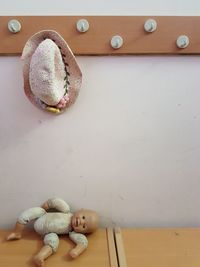 Hat hanging on rack over doll