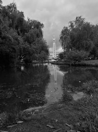 Reflection of trees on river against cloudy sky