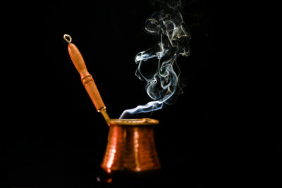 Close-up of smoke from traditional coffee cup against black background