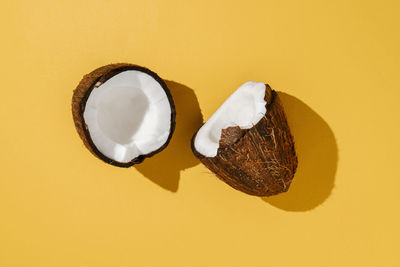 Two halves of coconut on a bright yellow background.