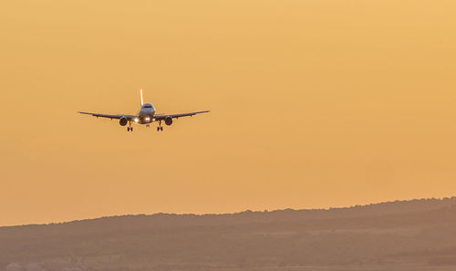 Low angle view of airplane flying in sky during sunset