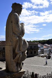 Statue in city against cloudy sky