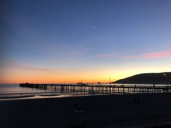 Scenic view of beach against clear sky during sunset