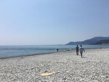 People on beach against clear sky