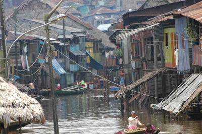 People on boats in canal amidst buildings in city