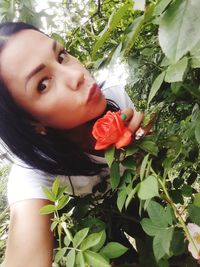 Portrait of beautiful woman against red flowering plants