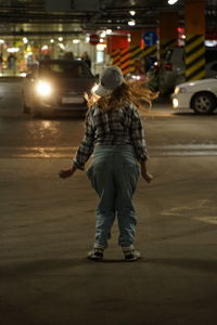 Rear view of man standing on road at night