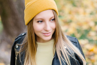 Smiling young woman in knit hat looking away