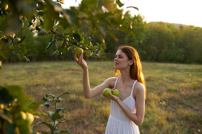 Young woman standing by tree