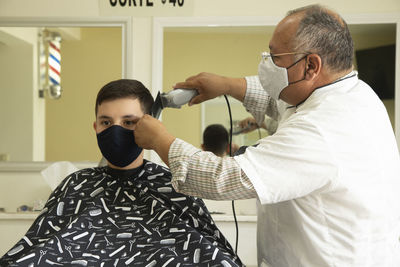 View of barber cutting hair of boy at barber shop