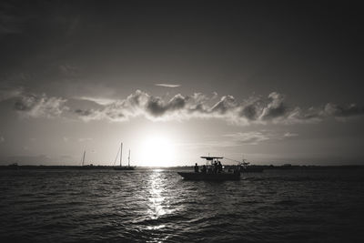 Silhouette sailboat in sea against sky during sunset