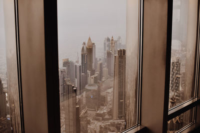 Buildings against sky seen through glass window