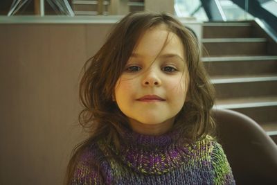 Close-up portrait of cute girl in sweater sitting on chair