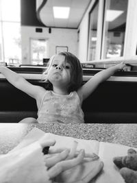 Portrait of cute girl making face while having food in restaurant