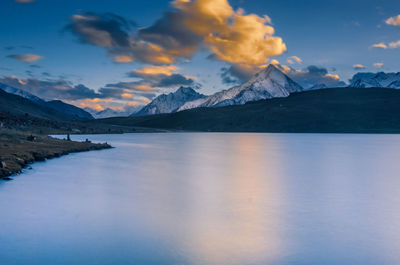 Scenic view of lake and mountains against sky during sunset