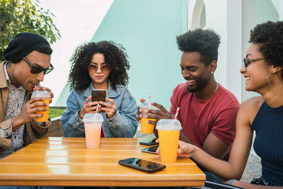 Portrait of happy friends sitting on table