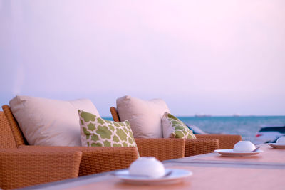 View of sofa with table against sea and sky