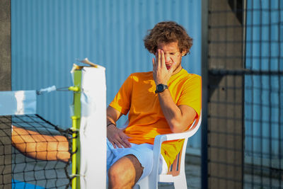 Tennis player sitting on chair at court